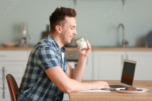 Young man with laptop drink...
