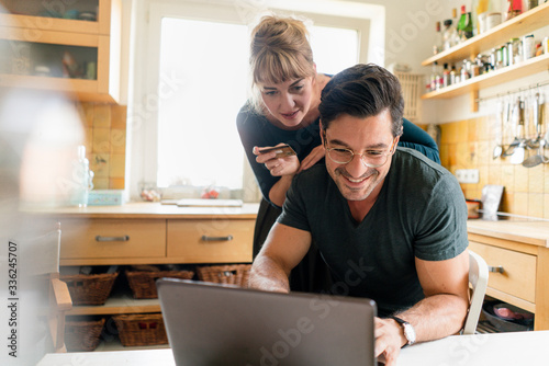 Happy couple shopping online in kitchen at home