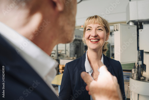 Happy businesswoman looking at businessman in a factory photo