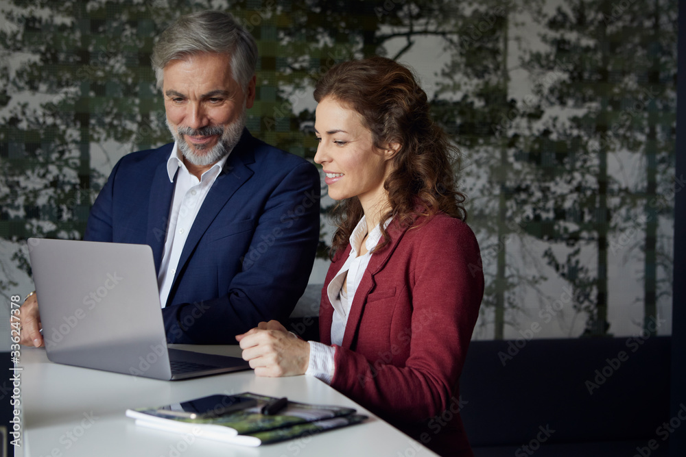 Businessman and businesswoman working together on laptop in office