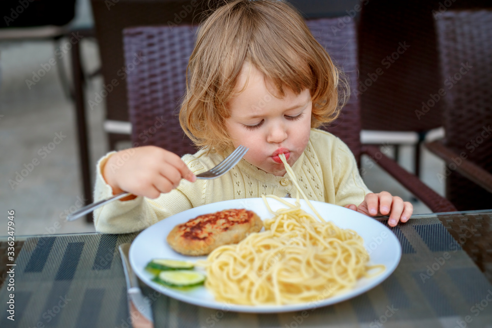 Adorable 2 years old little girl eating pasta and cutlet sitting in a cafe during her voyage, food and drink. Healthy eating for kids. Travel with young children Adorable 2 years old little girl eating pasta and cutlet sitting in a cafe during her voyage, food and drink. Healthy eating for kids. Travel with young children