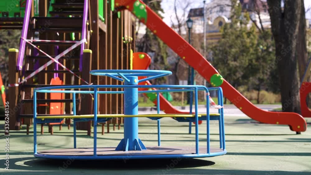 Abandoned carousel and slides with restriction tape on empty playground