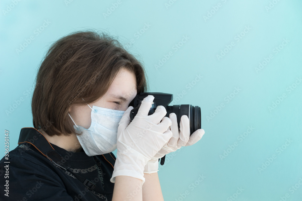 young female photographer in medical mask and white medical gloves makes photos with her camera on light blue backgrouund, protection from viruses and coronavirus pandemic, health care concept young female photographer in medical mask and white medical gloves makes photos with her camera on light blue backgrouund, protection from viruses and coronavirus pandemic, health care concept