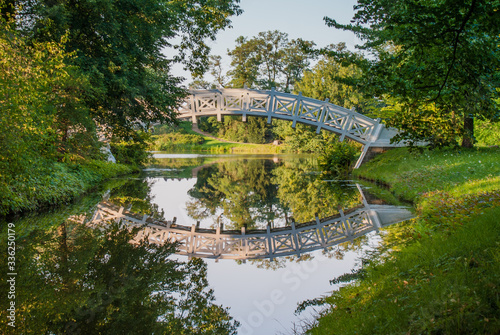 White pedestrian bridge with reflection in the water, Unesco Park Dessau-Wörlitz, Germany