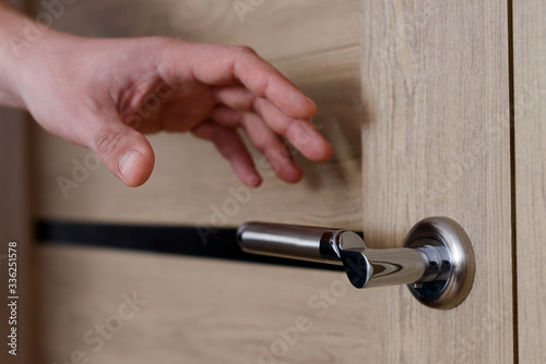 Close up of man’s hand reaching to door knob, opening the door