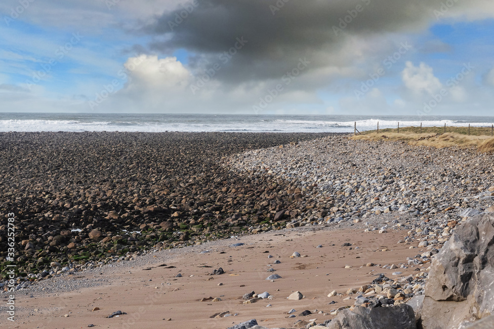 Rough stone beach and cloudy dramatic sky, Atlantic ocean, Wet and dry stone create S shape. Strandhill beach, county Sligo, Ireland. Rough stone beach and cloudy dramatic sky, Atlantic ocean, Wet and dry stone create S shape. Strandhill beach, county Sligo, Ireland.