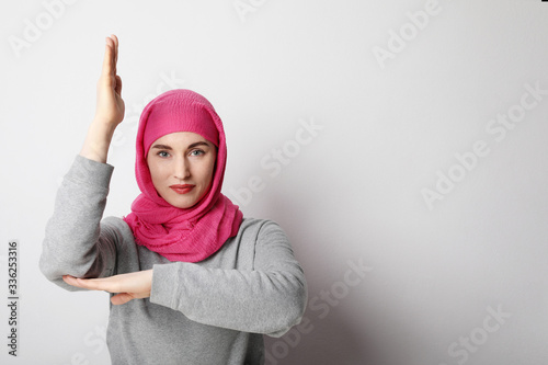 Close-up portrait of a muslim young woman wearing a hijab and putting hand up. Human rights concept. © face_reader_img