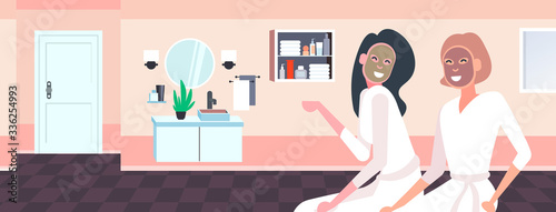 beautiful women applying face masks girls in bathrobes relaxing skincare spa facial treatment concept bathroom interior portrait horizontal vector illustration