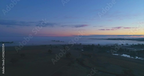 4K aerial video of a pretty pink sunrise on a foggy farm