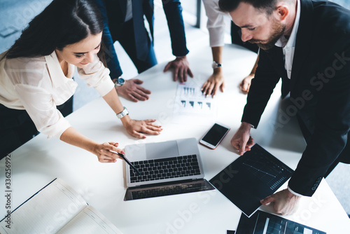 Coworkers inspecting laptop screen at workplace