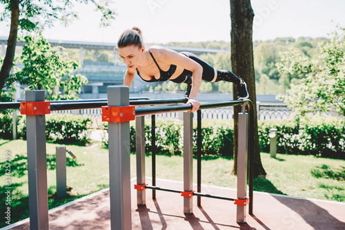 Fototapeta Naklejka Na Ścianę i Meble -  Young woman doing push ups on parallel bars