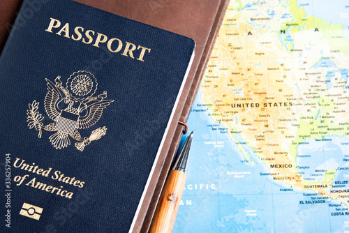 The foil-stamped dark blue front cover of an American passport set on a world map background.