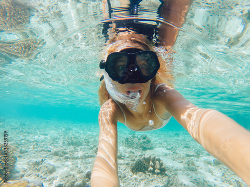 Young smiling blonde taking selfie underwater