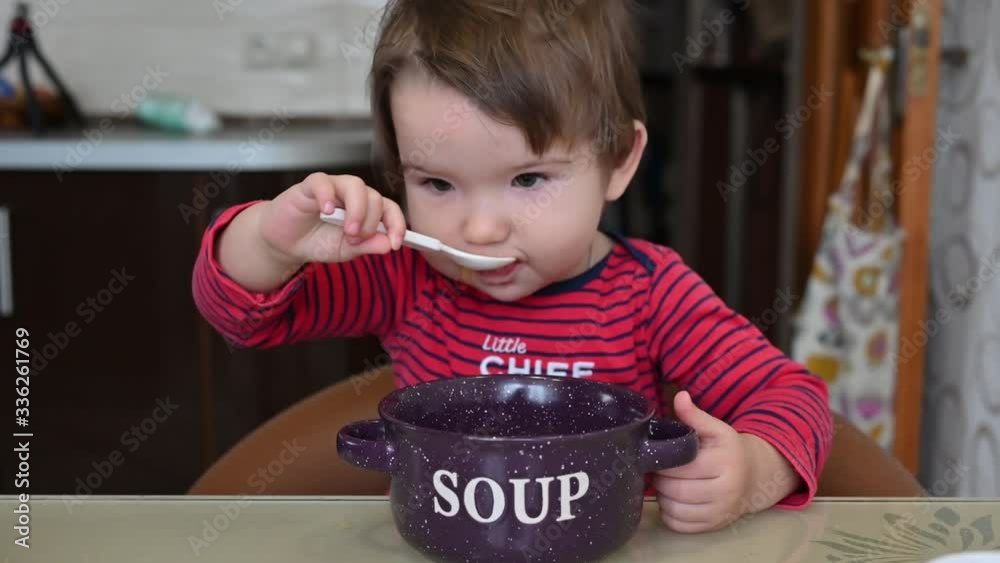 the child is eating soup. the child eats himself a spoon of soup the child is eating soup. the child eats himself a spoon of soup