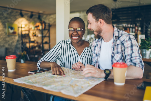 Laughing couple playing with map during organizing travel