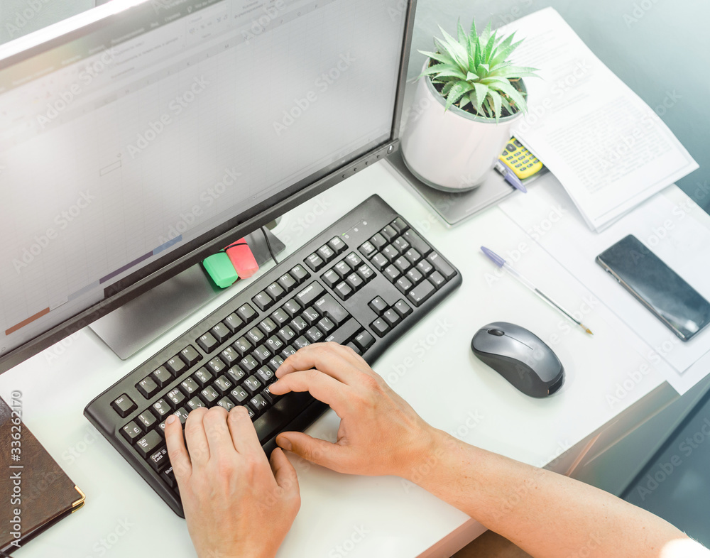 Male hands typing on computer keyboard sitting at white desk. Staying at home, working remotely, distance home office and frreelance job concept Male hands typing on computer keyboard sitting at white desk. Staying at home, working remotely, distance home office and frreelance job concept