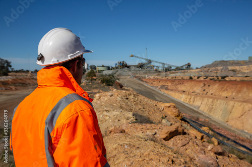 Unidentifiable miner in front of a copper mine portal road, with minehead in background in NSW Australia photo