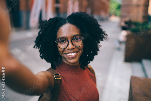 Young smiling black woman taking selfie in city