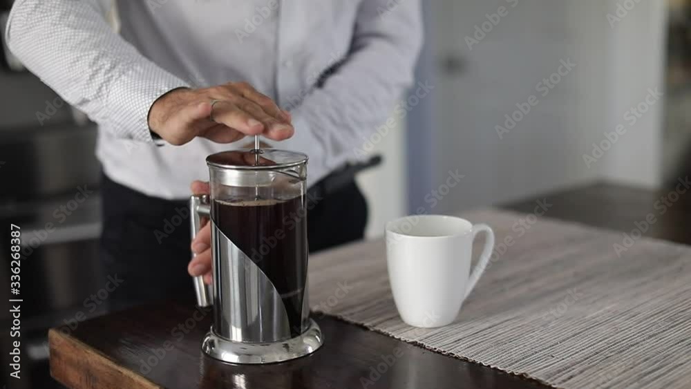 Man making a coffee with french press. Caucasian man pouring coffee in coffee cup at kitchen in a comfortable home. Slow Motion.