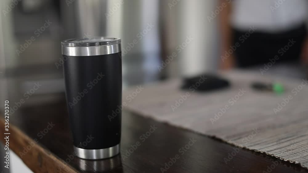 Man taking car key, wallet and tumbler with coffee out of table. Close up of hand taking tumbler with coffee to go in the kitchen. Slow motion.