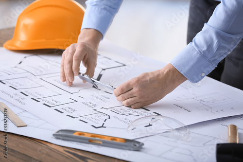 Male builder working with house plan in office