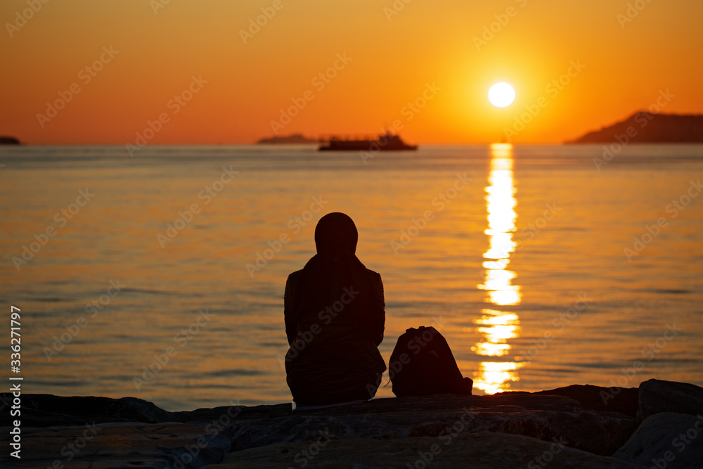 Silhouette of a muslim woman watching the sea of Marmara sunset in Maltepe, Istanbul, Turkey