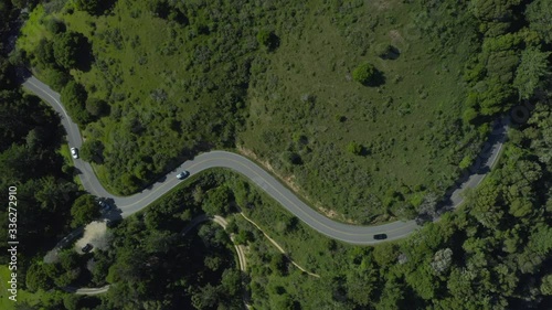 Aerial video of a winding road with cars on a green mountain road shot in 4k