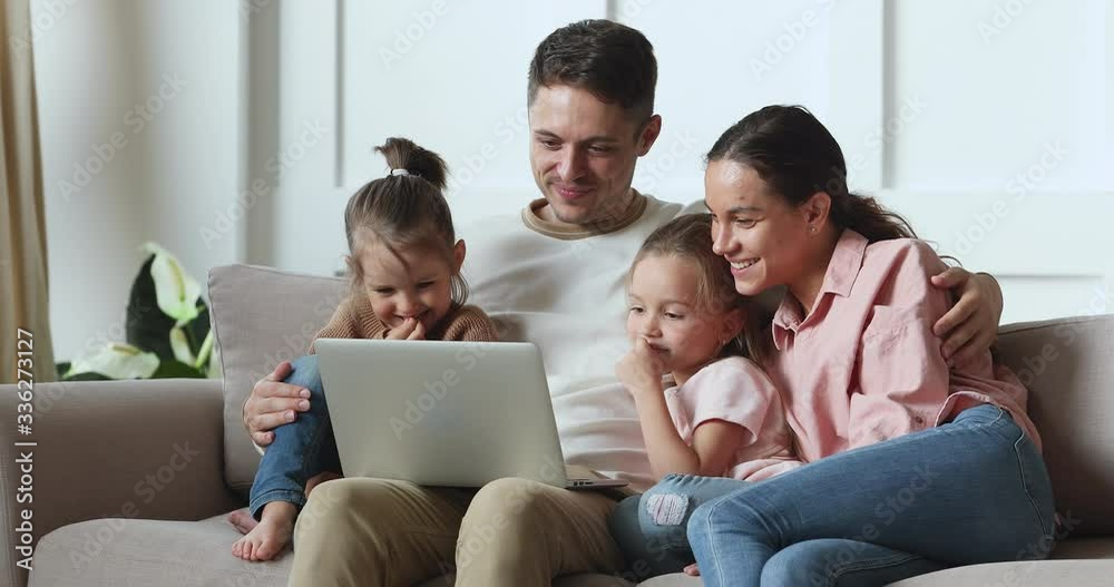 Smiling handsome young father embracing pretty wife and adorable little preschool kids daughters, watching funny movie cartoons on laptop. Happy family couple shopping online with children at home. Smiling handsome young father embracing pretty wife and adorable little preschool kids daughters, watching funny movie cartoons on laptop. Happy family couple shopping online with children at home.