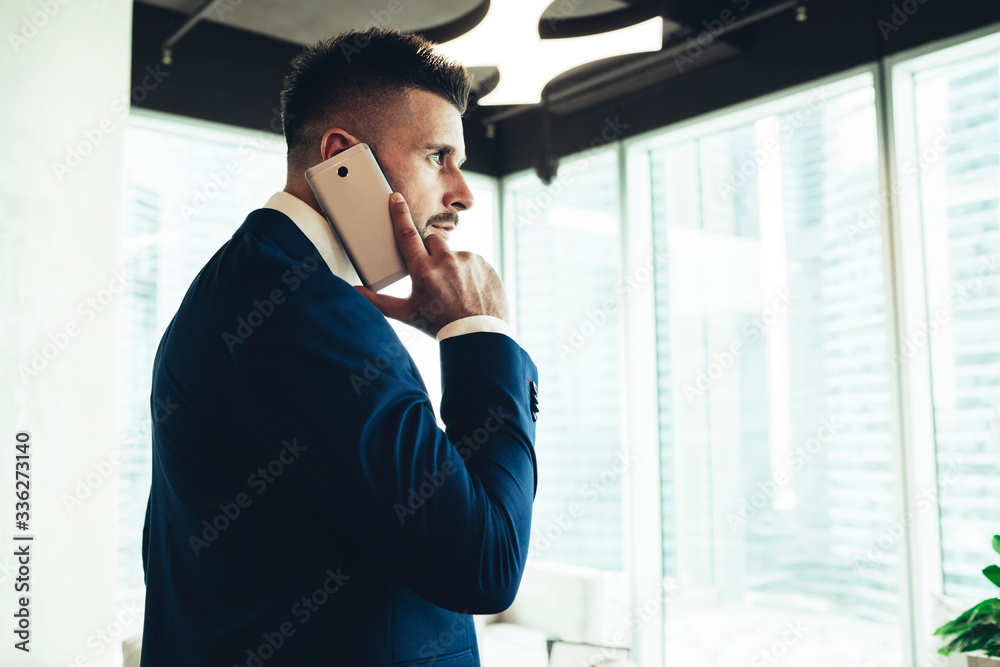Successful male executive in suit talking on smartphone at office Successful male executive in suit talking on smartphone at office