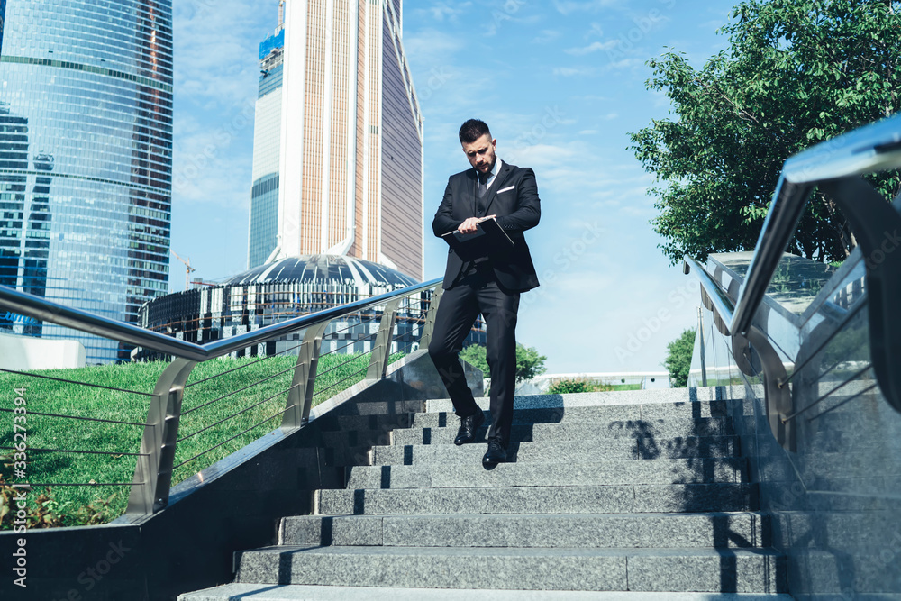 Businessman checking time while walking down stairs