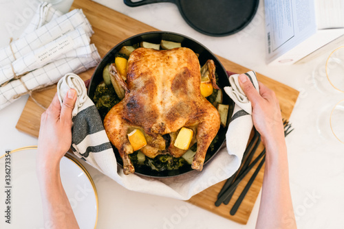 Hot and fresh oven-roasted whole chicken with lemon and garlic in a red dutch oven