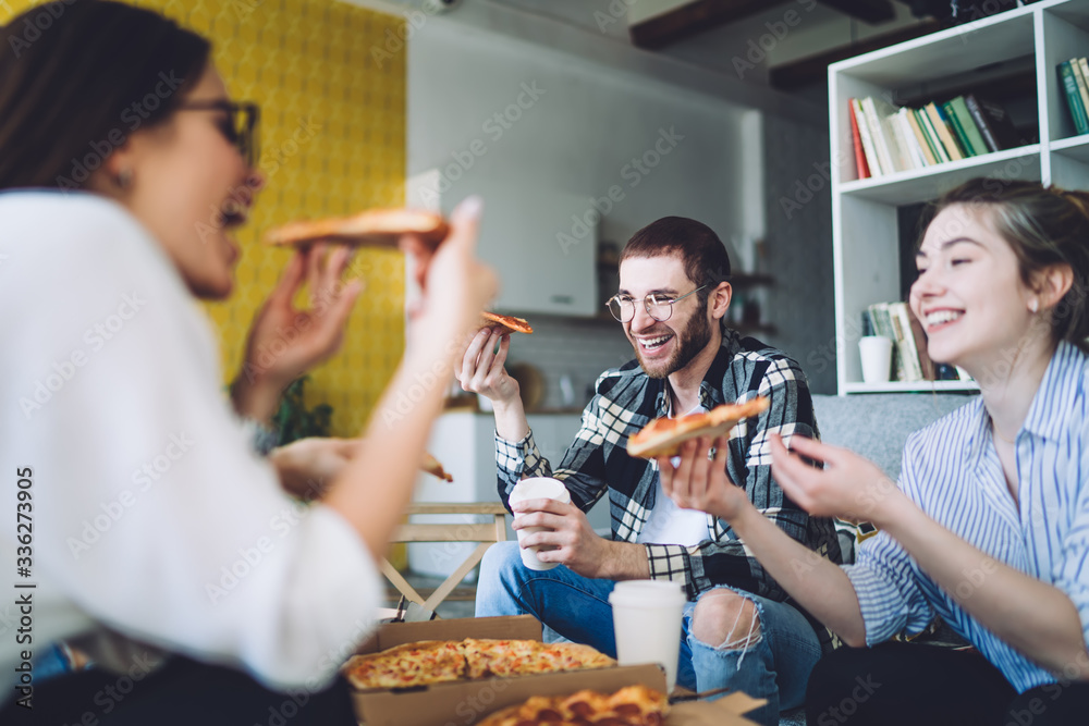 Laughing friends enjoying pizza during party