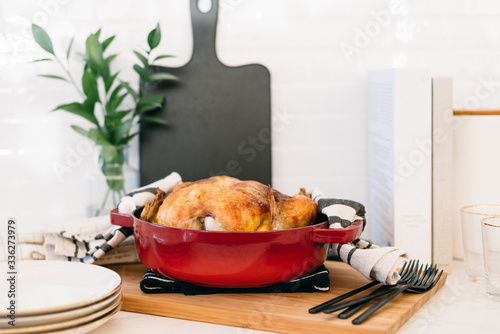 Hot and fresh oven-roasted whole chicken with lemon and garlic in a red dutch oven