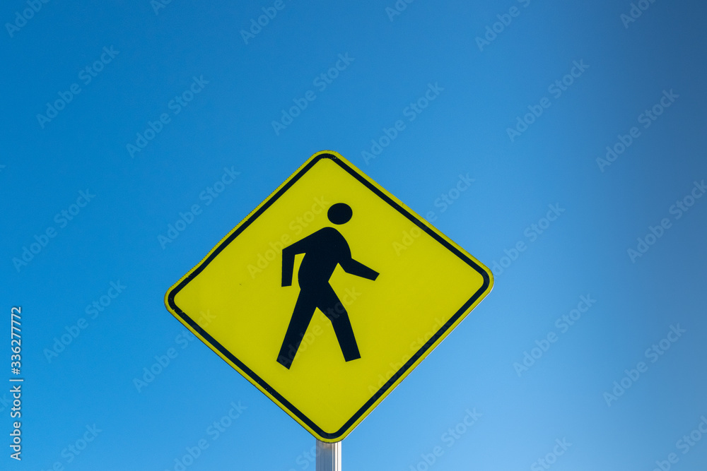 A yellow warning sign advising that pedestrians are crossing, copyspace above A yellow warning sign advising that pedestrians are crossing, copyspace above