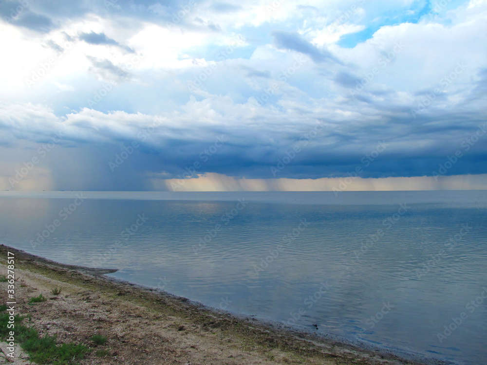 Clouds and rain over the smooth surface of the lake. Lake Sivash, Crimean peninsula. Clouds and rain over the smooth surface of the lake. Lake Sivash, Crimean peninsula.