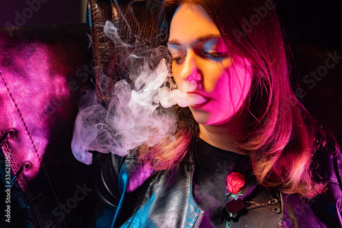 A woman blows smoke from ci...