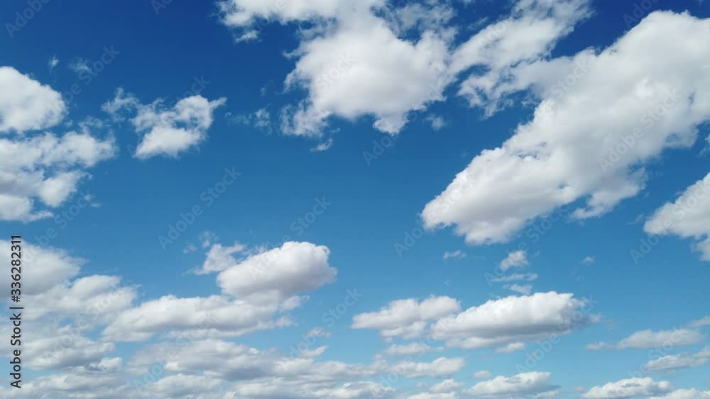 Puffy clouds rolling & twisting across the blue sky
