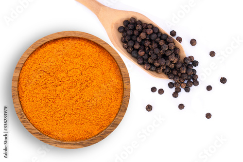 curcumin powder ( tumeric ground, turmeric, Curcuma ) in wooden bowl and black pepper corn in  spoon isolated on white background. Health benefits and antioxidant food concept. Top view. Flat lay.  photo