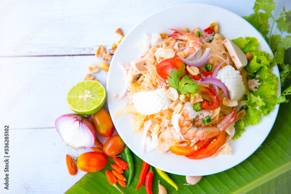 Spicy Vermicelli Seafood Salad with vegetable ingredient on wood white background, Thai food Street food Concept.Top View Spicy Vermicelli Seafood Salad with vegetable ingredient on wood white background, Thai food Street food Concept.Top View