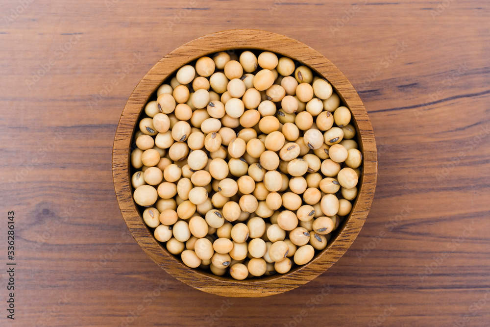 Closeup soy beans in wooden bowl isolated on wood table backgroun. Closeup soy beans in wooden bowl isolated on wood table backgroun.