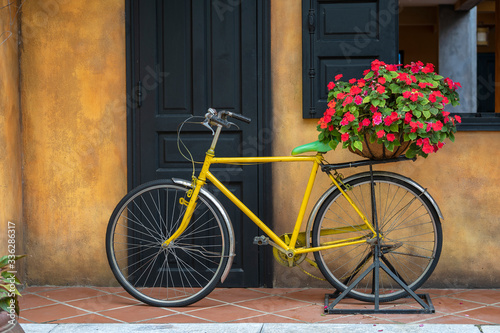 Yellow vintage bike with basket full of flowers next to an old building in Danang, Vietnam © OlegD