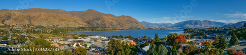 A wide panoramic view across the town of Wanaka to Lake Wanaka and the southern alps mountain range.