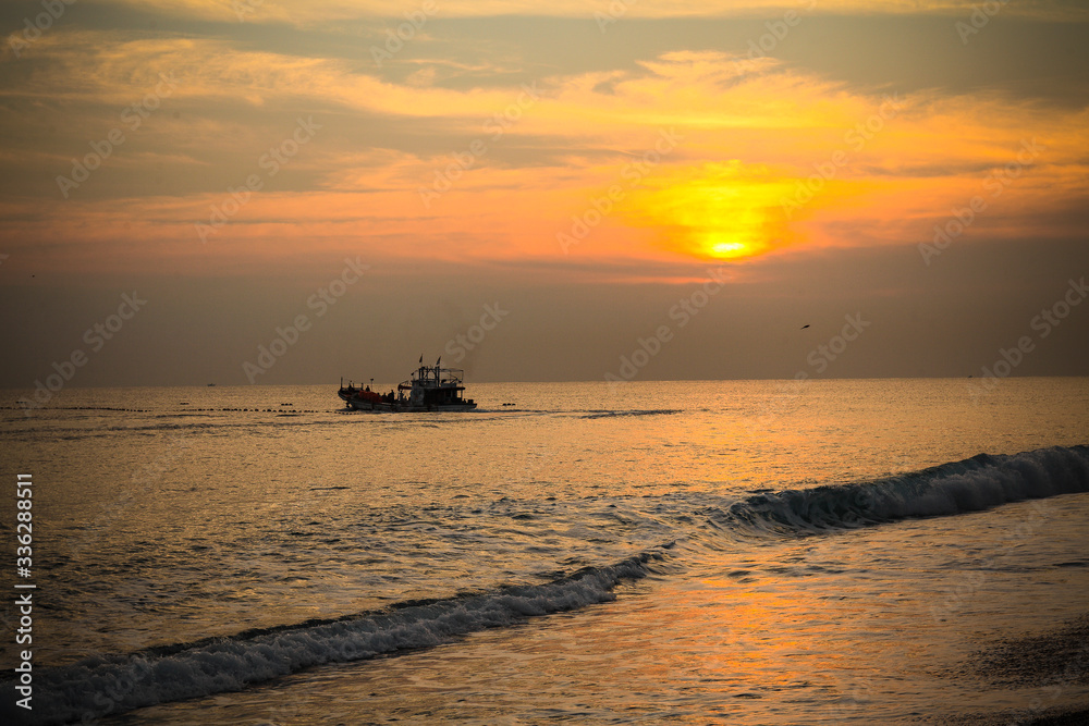 Chinese fishing junks plowing the seas at sunset. 