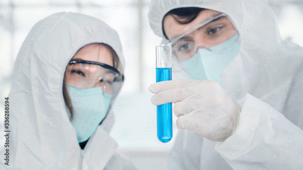 scientific background of biological reseach scientists in biohazard protection clothing experimenting and holding test tube on hand in laboratory scientific background of biological reseach scientists in biohazard protection clothing experimenting and holding test tube on hand in laboratory