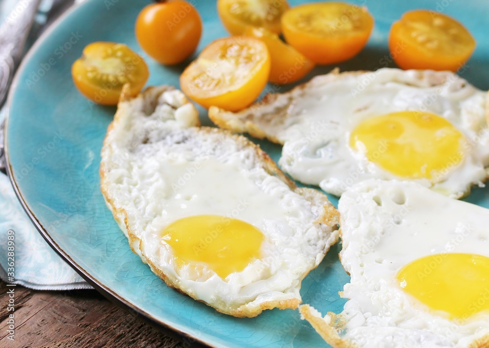 sunny breakfast life style, fried eggs and yellow cherry tomatoes. on a blue plate. yellow and blue sunny breakfast life style, fried eggs and yellow cherry tomatoes. on a blue plate. yellow and blue