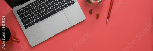 Top view of workspace with laptop, coffee cup and copy space on pink table