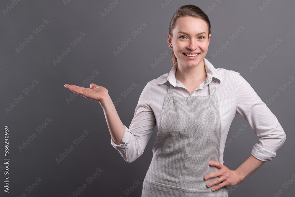 Girl chef in apron shows a hand on a black background. Recipe book and homemade recipes Girl chef in apron shows a hand on a black background. Recipe book and homemade recipes