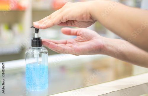 Female hand pressing alcohol gel or sanitizer pump bottle for washing hand in hospital or public area.