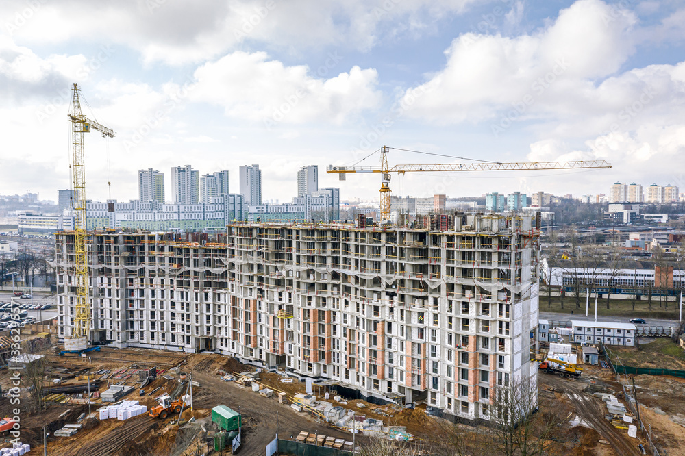 city construction site with yellow tower cranes and machinery. aerial top view of residential construction area.