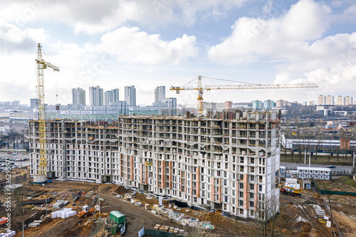 city construction site with yellow tower cranes and machinery. aerial top view of residential construction area.